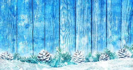 Christmas trees and cones background on blue wooden board and snowの写真素材