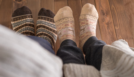 couple with woolen socks sitting on wooden floor, winter cosy sceneの写真素材