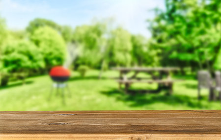 summer time in backyard garden with grill BBQ, wooden table, blurred backgroundの素材 [FY310203775646]