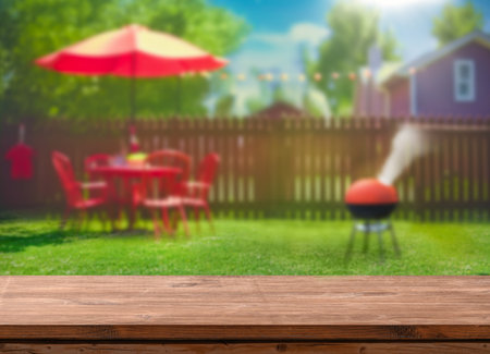 summer time in backyard garden with grill BBQ, wooden table, blurred backgroundの写真素材