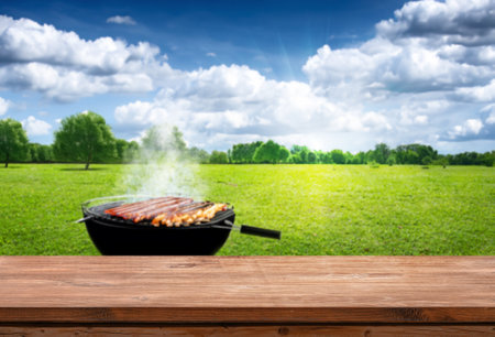 summer time outdoors with grill BBQ, wooden table, blurred backgroundの写真素材