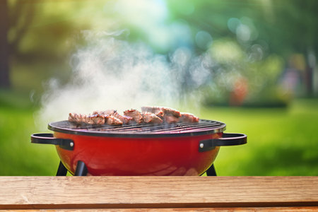 summer time party in backyard garden with grill BBQ, wooden table, blurred backgroundの写真素材
