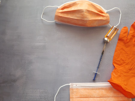 on a gray background, a vaccine, a syringe, orange medical masks and gloves. High quality photoの写真素材