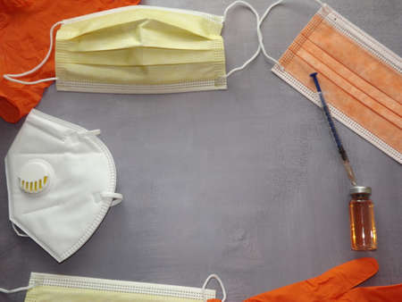 on a gray background, a vaccine, a syringe, orange medical masks and gloves. High quality photoの写真素材
