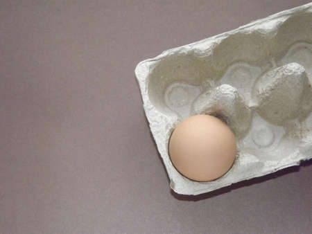 beige boiled eggs in a pot of water with an egg box on a gray background. High quality photo