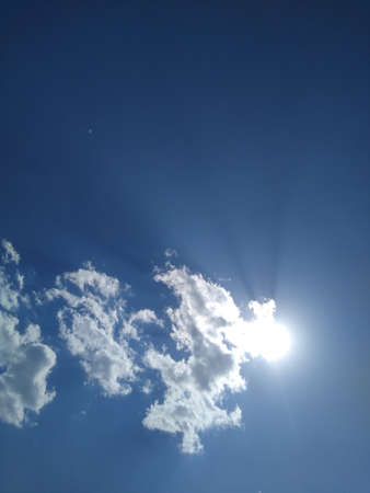 the sun is behind a small dot in the blue sky. High quality photo
