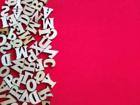 wooden letters of the alphabet scattered on a red background with space for text. High quality photoの写真素材
