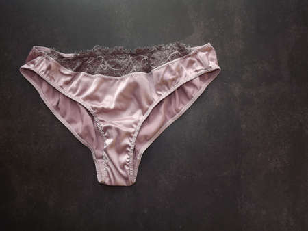 Silk light pink womens panties on a black background. High quality photoの写真素材