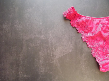 Burgundy crimson lace guipure thong for women on a black background. High quality photoの写真素材