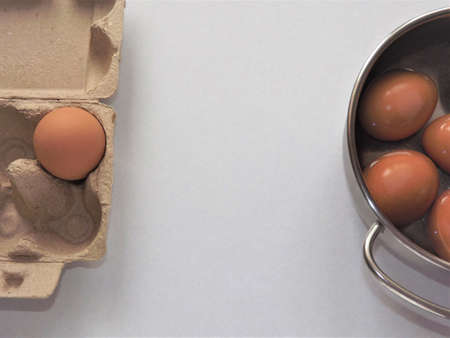 beige boiled eggs in a pot of water with an egg box on a gray background. High quality photo