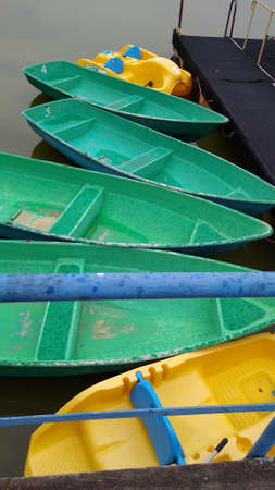 Pleasure boats of green and yellow colors are standing on the pier in the rain. High quality photoの写真素材