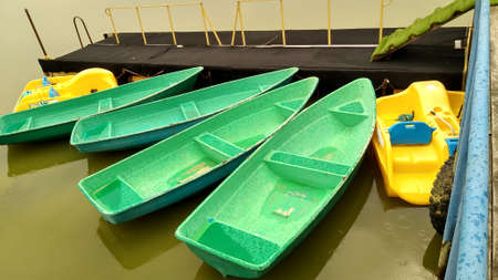 Pleasure boats of green and yellow colors are standing on the pier in the rain. high quality photoの写真素材