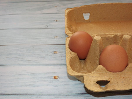 chicken eggs in an egg box on wooden background. high quality photo