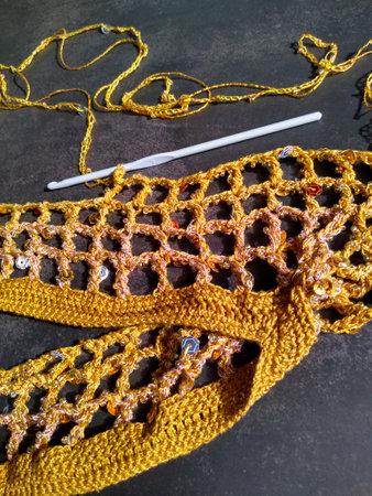 The process of crocheting from beads and sequins of golden color. Making a dress for a merry...