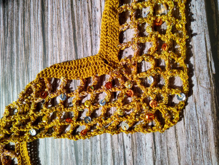 The process of crocheting from beads and sequins of golden color. Making a dress for a merry...