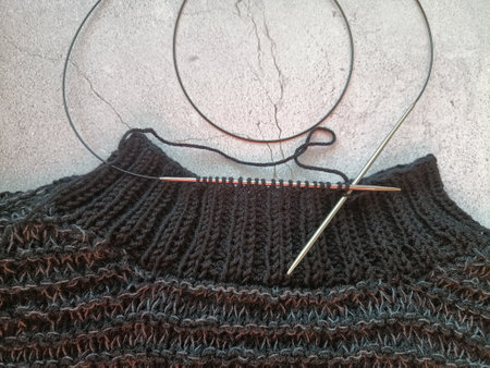 The process of knitting a jumper made of black and gray wool. High quality photo