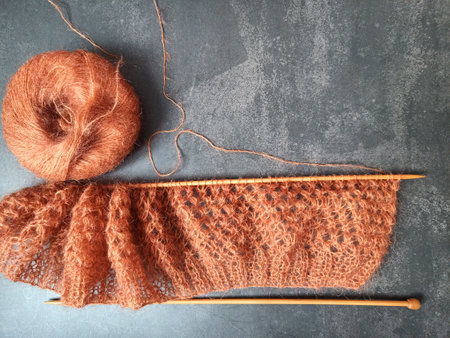 The process of knitting a jumper or sweater made of pink mohair yarn with wooden knitting needles....
