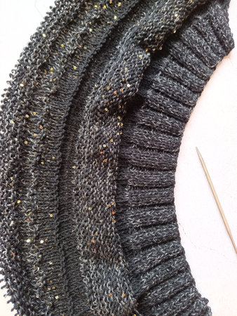 The process of knitting a jumper made of black and gray wool with sequins. High quality photo