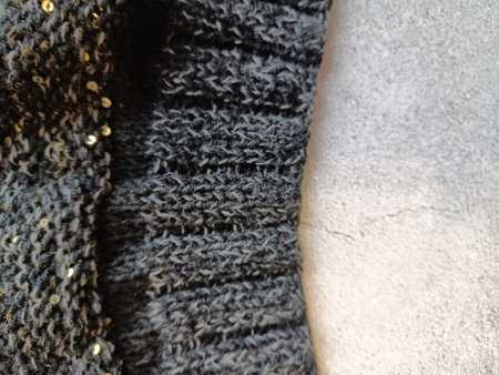 The process of knitting a jumper made of black and gray wool with sequins. High quality photo