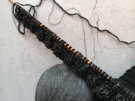 The process of knitting a jumper made of black and gray wool with sequins. High quality photo