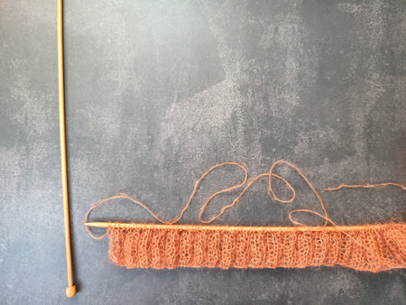 The process of knitting a jumper or sweater made of pink mohair yarn with wooden knitting needles....