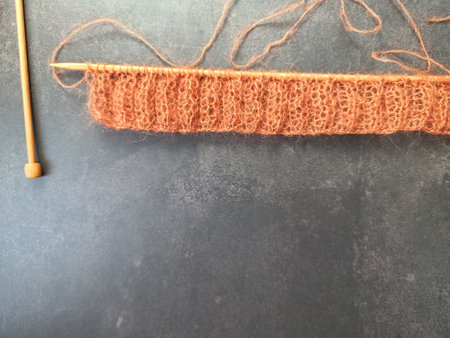 The process of knitting a jumper or sweater made of pink mohair yarn with wooden knitting needles....