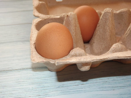 chicken eggs in an egg box on wooden background. High quality photo
