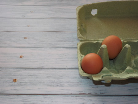 chicken eggs in an egg box on wooden background. High quality photo