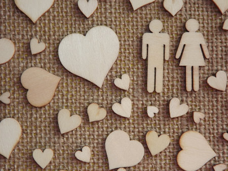 wooden hearts of different sizes and figurines of a man and a woman on jute fabric as a Valentine's day card. Declaration of love. High quality photoの写真素材