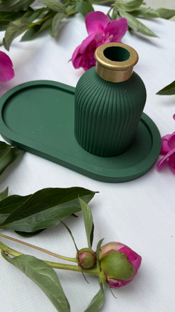 Green vase with peony flowers on a white tableclothの写真素材