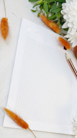 Notebook, pen and flowers on a white background. Space for text.の写真素材