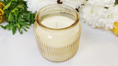 Aroma candle in a glass jar with flowers on a white backgroundの写真素材