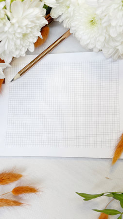 Blank notebook, pen and flowers on a white tablecloth.の写真素材