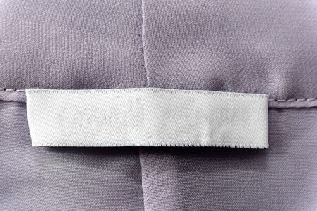 white blank clothes label on worn pink gray shirt background