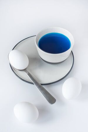 Coloring traditional Easter eggs with bright pigment on white background. Spring holiday symbols. Christian gift concept.の写真素材