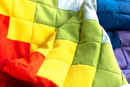 Rainbow patchwork quilt fragment. Colorful handmade ethnic blanket. Worn clothes reuse concept.