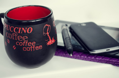 Modern workplace with digital tablet computer and mobile phone, cup of tea, pen and paper with numbers.の写真素材