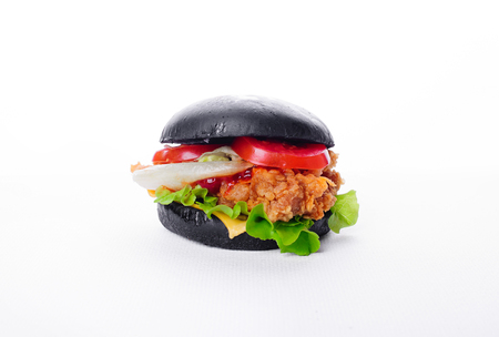 Black burger with chicken cheese lettuce onion, tomato and sauce served  white backgroundの写真素材