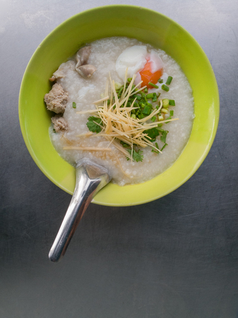 Rice porridge is topping with ginger spring onion pepper chicken and onsen egg Breakfastの写真素材