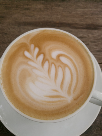Cup of tasty cappuccino on the wooden textured table. Cappuccino is in the white big cup.の写真素材