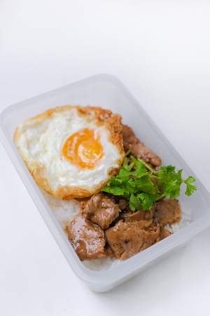 Fried pork with garlic pepper and fried egg on rice in box isolated selective focus copy spaceの写真素材