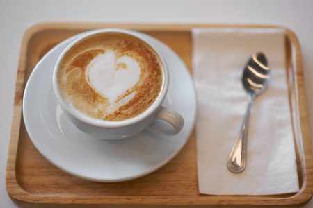 Hot mocha coffee or capuchino with heart pattern on the wooden tableの写真素材