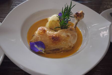 Roasted chicken breast served with potato and yellow sauce in white plateの写真素材