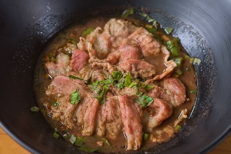 White noodle soup with meatball and beef stewed served in a black bowl. In Thailand, we call this...