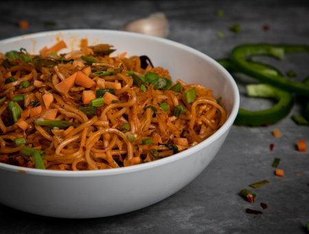 Fried noodles with vegetables in a white bowl on a dark backgroundの写真素材