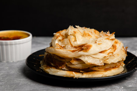 PAROTTA:
an Indian bread made with refined flour which is cooked to flaky crispness and served with...