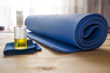 Blue yoga mat with cleaner on wooden background.Home practice.の写真素材