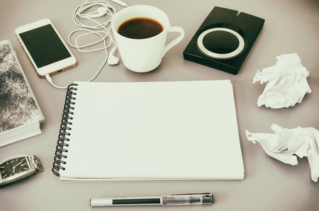 Business workplace.  Top view of grey office desk  with coffee cup, diary, notepad, pen, memory disk, smartphone and earphone. Copy space.の写真素材