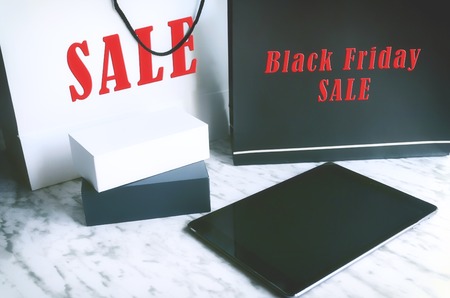 Shopping bag , smatphone boxes and black tablet on grey background. Black Friday sale conceptの写真素材