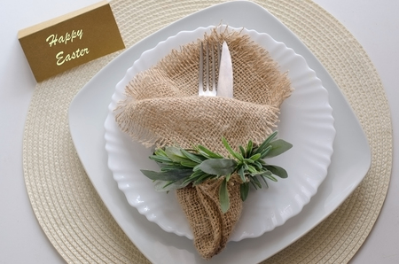 Festive Easter table setting. Silver Knife and Fork with rustic napkin in the nest